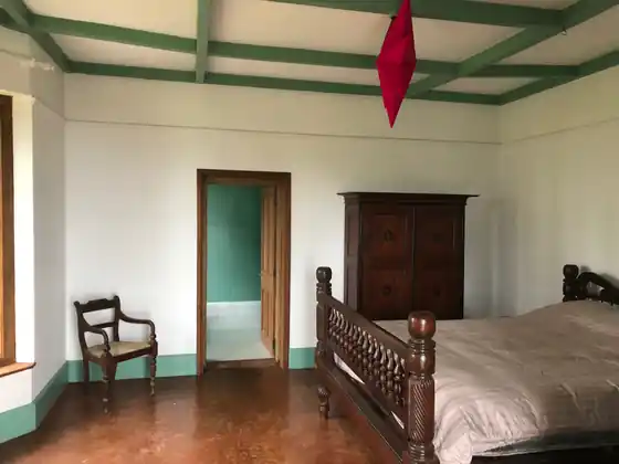 Bungalow bedroom with a carved wooden bed and antique wardrobe