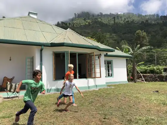 Children playing on the lawn in front of the bungalow, with the hills rising behind
