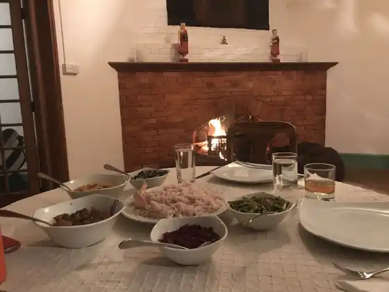 Bowls of home-cooked curries laid out on the table by the open brick fireplace