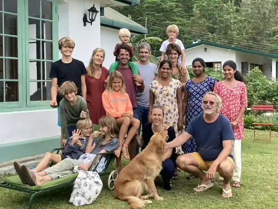 A happy group of family and friends with a dog on the lawn outside the bungalow