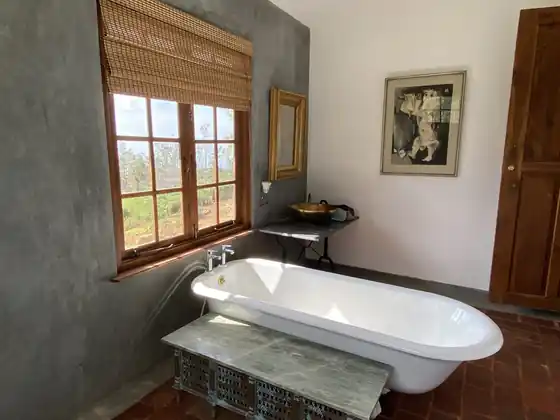The Library Suite bathroom: a white clawfoot bath beneath a tall window, with grey and white walls and a gilt mirror