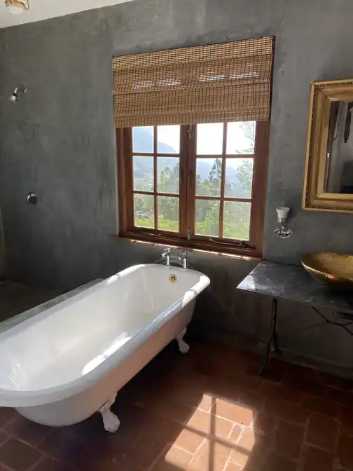 A clawfoot bath beneath a window in the Library Suite bathroom, with hill views