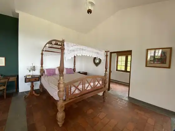The carved four-poster bed in the Library Suite, with brick-red floor and white walls