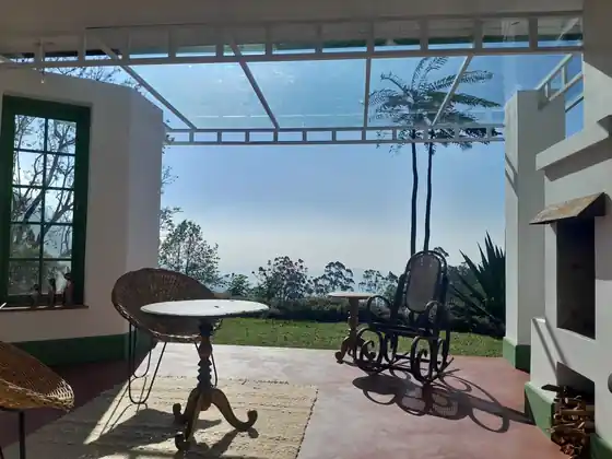 Chairs and a small table on a covered terrace looking out over the hills